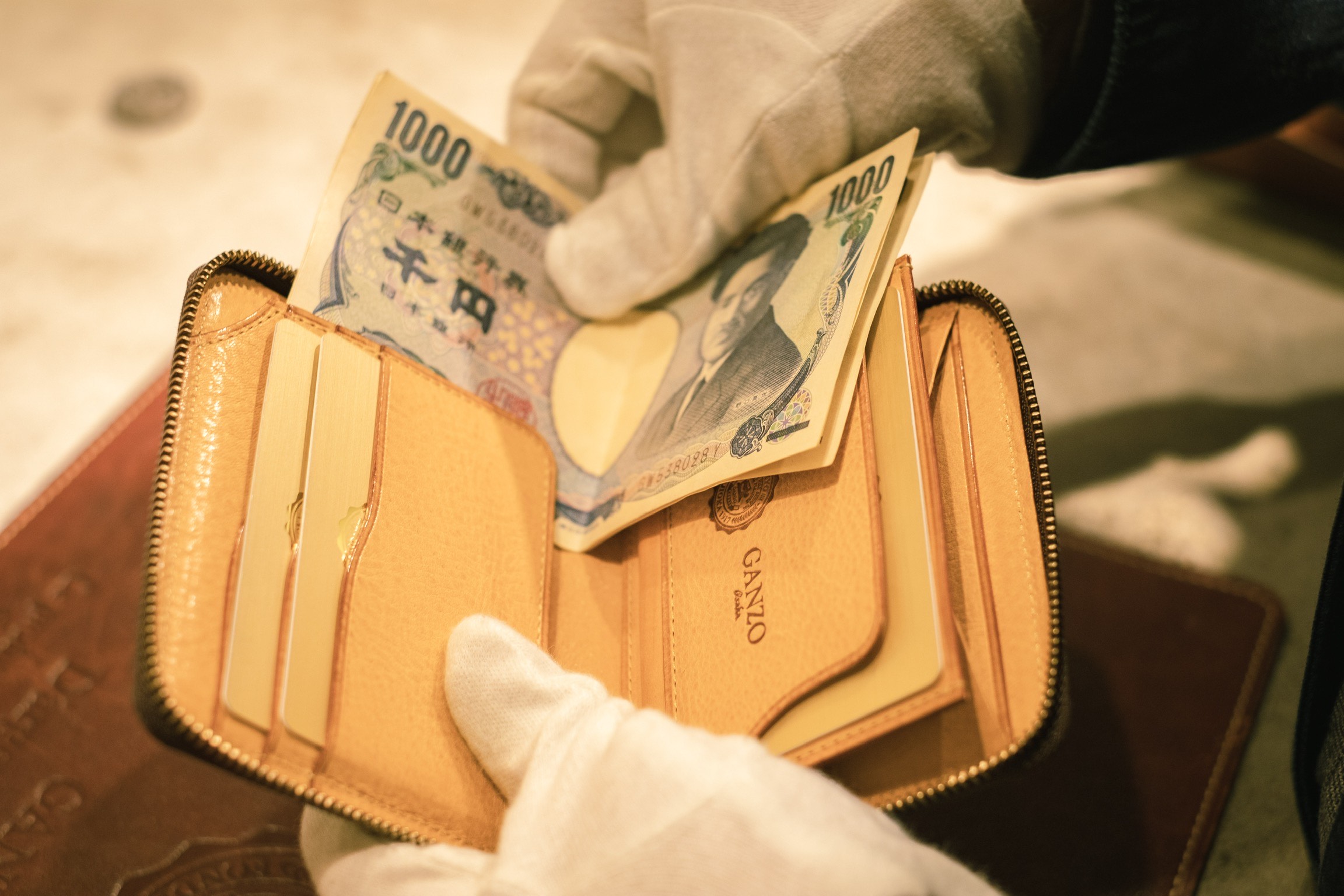 大阪店限定のコンパクトジップウォレットにお札を入れる写真